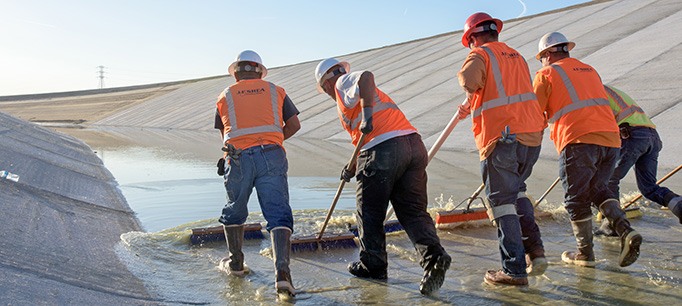 Contracts in orange vests with an assistance with a California Department of Water Resources worker, perform final close-out repairs at the Pool 30 project.
