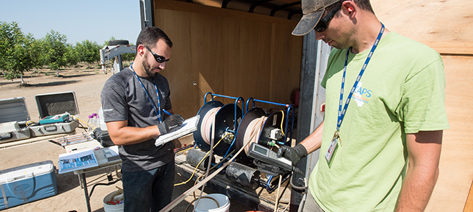 Fish and Wildlife Scientific Aid Brian Bettencourt (left) records data while Environmental Scientist Evan MacKinnon (right) reads off water quality parameters from a multi-parameter water quality meter at a well in Sutter County, California for the Department of Water Resources